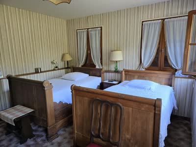 Chambre avec deux lits bateau en bois et fenêtres à rideaux blancs