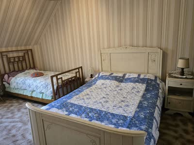 Chambre mansardée avec un lit double à couvre-lit bleu et un lit simple en bois
