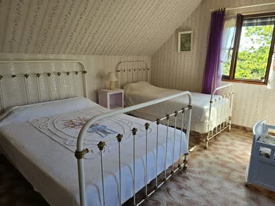 Chambre sous rampant avec deux lits en fer forgé blanc et dessus-de-lit blancs