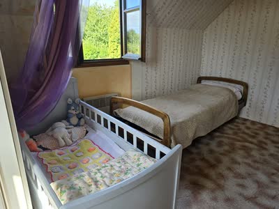 Chambre mansardée avec un lit simple et un lit à barreaux pour enfant