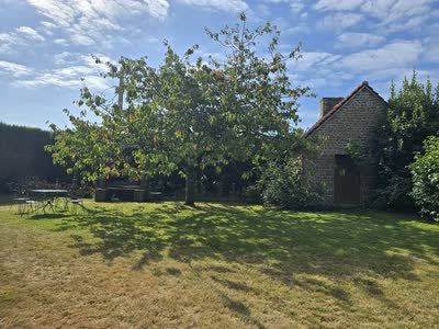 Salon de jardin en fer forgé sous le cerisier, devant une dépendance en pierre