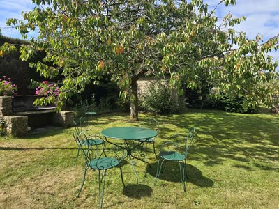 Table et chaises vertes en fer forgé et barbecue en pierre dans le jardin