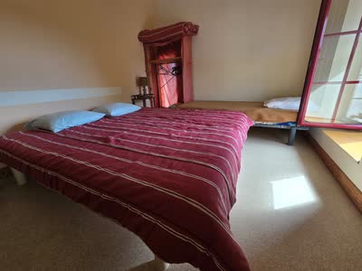 Chambre du gîte avec un grand lit et un lit d'appoint sous le rampant
