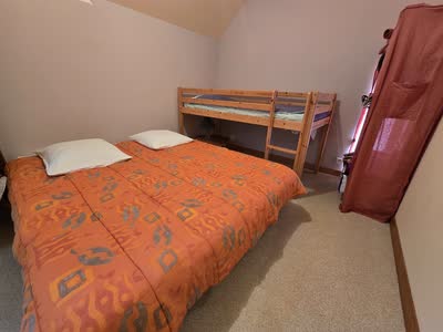 Chambre du gîte avec un lit double et un lit superposé en bois clair