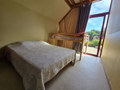 Chambre du gîte avec un lit double et un lit superposé, ouverte de plain-pied sur la terrasse