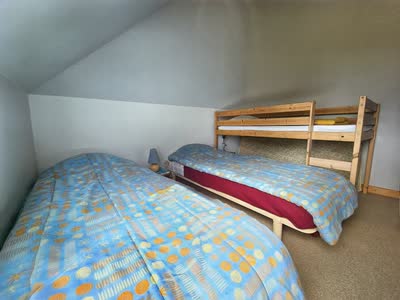 Chambre mansardée du gîte avec un lit simple et un lit superposé