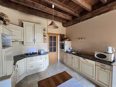 La cuisine équipée du gîte sous ses poutres anciennes, avec four, micro-ondes et grand plan de travail
