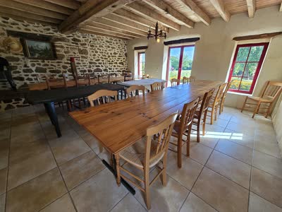 La grande salle du gîte, son mur en pierre apparente, ses poutres et ses deux grandes tablées