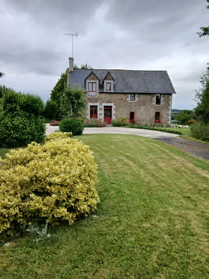 La maison en pierre à lucarnes vue depuis la pelouse, fusain panaché au premier plan